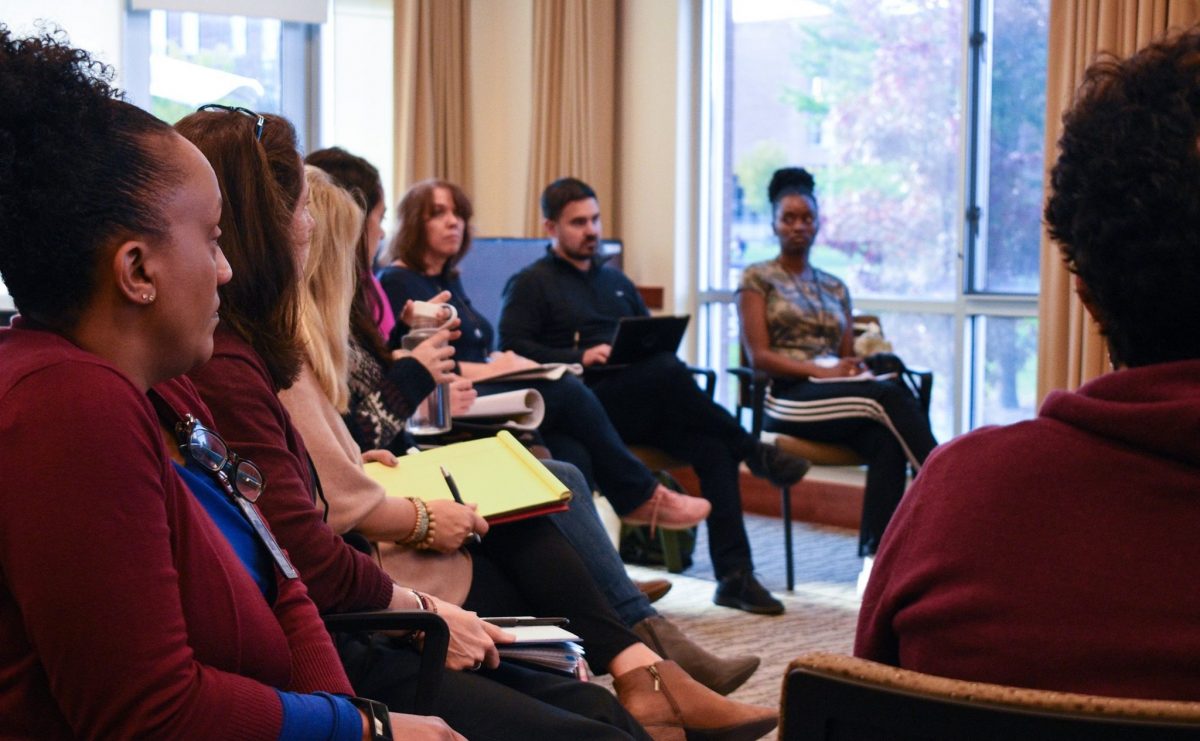 8 adults in semi-circle listen to discussant