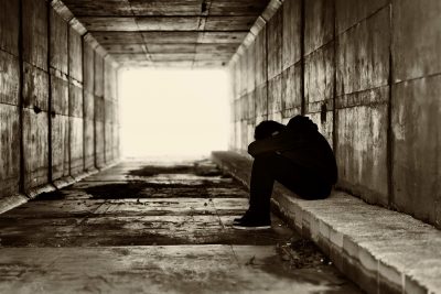 Silhouette of a boy in a tunnel covering head with hands