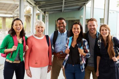 A group of smiling teachers hanging out in school corridor