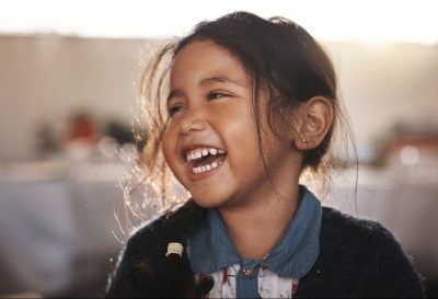 little girl with earrings looks to her right and smiles