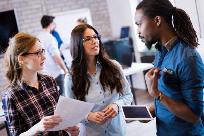 Diverse group of young people talking in office space