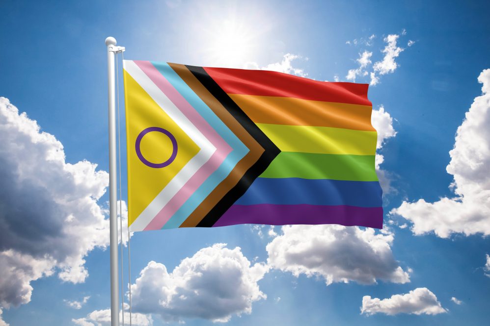 pride flag against sky with sunshine and white clouds
