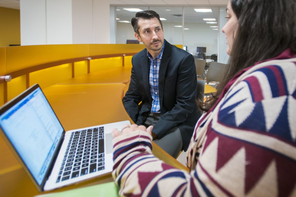 Nathanael Okpych, an associate professor in the School of Social Work, talks to a student in 2018. (Sean Flynn/UConn Photo) 