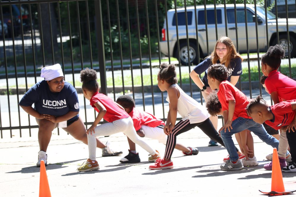 Two UConn College students leading children in exercises outside (UConn HNS photo)