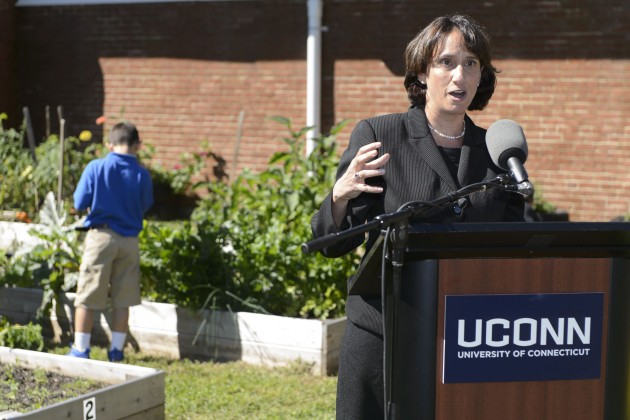 Marlene Schwartz speaks at podium with UConn sign on front.