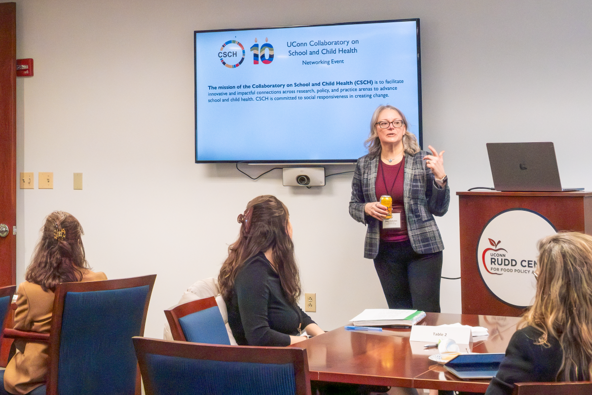 Sandra Chafouleas speaks at a networking event in Hartford. She stands in front of a screen with the CSCH logo and the CSCH mission